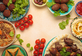 Frame composition of middle eastern or Arab dishes and assorted meze on light beige background. Meat kebab, falafel, hummus, sambusak, rice, kibbeh, pita. Halal food. Lebanese cuisine, copy space