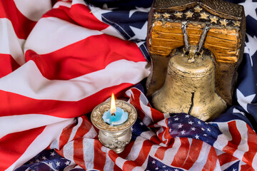 USA bell, candle rest on an American flag, symbolizing liberty remembrance symbol of freedom in reflective moment.