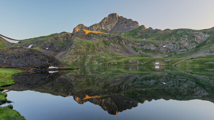 Mountain peak reflecting in a lake at sunrise in the pyrenees mountains.