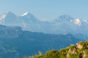 The Berner Oberland region blends dramatic alpine peaks with rolling green hills, dotted with...