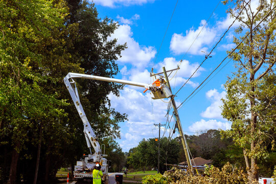 Utility crew operates cherry picker to restore power lines in neighborhood affected by inclement weather conditions.