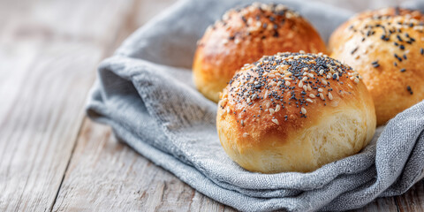 Golden, fluffy buns topped with sesame and poppy seeds rest on a soft linen cloth, exuding warmth and inviting comfort for any meal or snack.