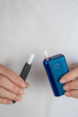 A woman compares two different tobacco heating systems. Electronic cigarette.