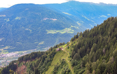 Beautiful alpine landscape with a small house on a green slope overlooking the Adige valley and...