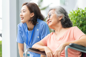An empathetic caregiver crouches to listen to a senior woman in a wheelchair, demonstrating respect...