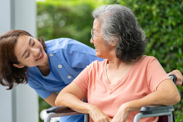 An empathetic caregiver crouches to listen to a senior woman in a wheelchair, demonstrating respect...