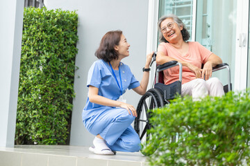 An empathetic caregiver crouches to listen to a senior woman in a wheelchair, demonstrating respect...
