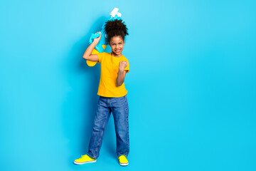 Joyful young schoolgirl posing with energetic gestures against a colorful background wearing a...