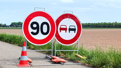 Speed limit signs indicating 90 km/h with construction cones. Temporary speed restrictions for...