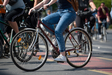 Woman on bicycle against many bicyclist riding on a street