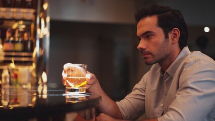 Sitting smart man drinking alone of cocktail Old fashioned waiting friends or couple at bokeh lighting at luxurious beverage counter nightclub at pub and restaurant on Friday meeting night. Vinosity.
