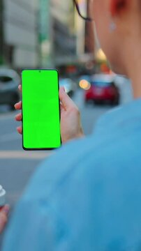 Woman is standing on the street and using smartphone with green screen