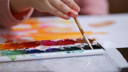 Young artist dipping brush in black watercolor