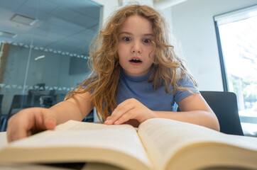 Funny child reading book. Schoolkid studying and reading. Smart kid read book. Little student learning from book. Child reading book in library. Education and Learning. Knowledge through reading.