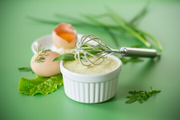 homemade mayonnaise with herbs in a bowl on a green background