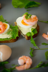 Light sandwich with seafood and greens on gray background