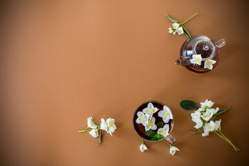 Tea composition with green tea and jasmine flowers on a brown background