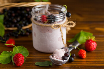 Blackcurrant ice cream with strawberries on wooden background