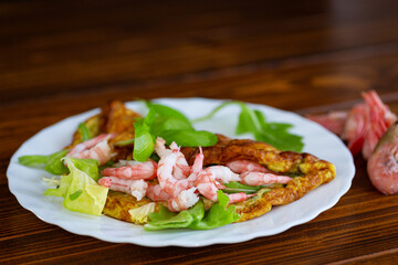 Omelette with seafood and greens on a white plate