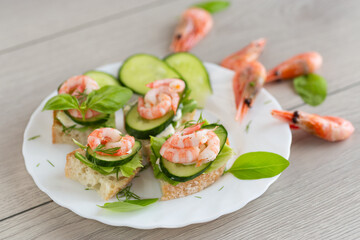 Portioned appetizers with shrimps, lettuce and sauce on a wooden table