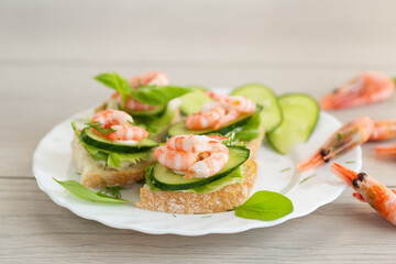 Mini canapes with shrimps, lettuce and cucumber, on a wooden table