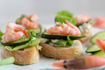 Delicious portioned appetizers with shrimps and greens on a wooden table