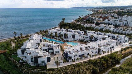 Aerial view of a luxury apartments in Estepona, featuring multiple pools, lush gardens, and modern...