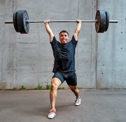 Weightlifting athlete performs overhead lift in urban gym setting