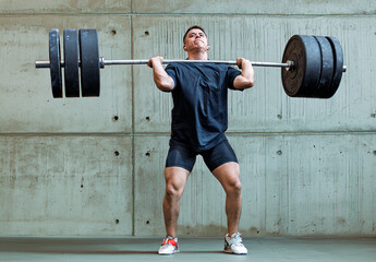 Weightlifting athlete performs a clean and jerk in a gym