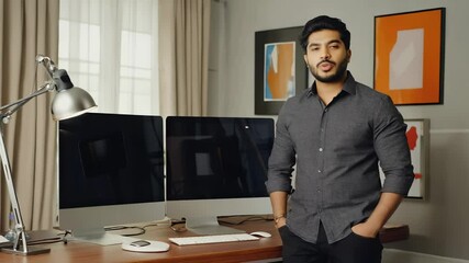 Confident Young Man Standing in a Modern Home Office with Dual Computer Monitors