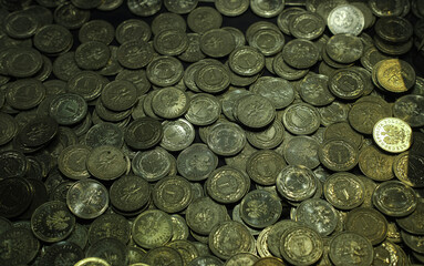 A pile of Polish 1 grosz coins, mostly dark and aged, with one shiny coin standing out, illuminated under moody lighting.