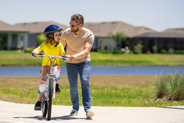 Happy fathers day. Father and son learning to ride a bicycle having fun together at Fathers day. Father teaching his son cycling on bike in american neighborhood. Father and son concept. Father