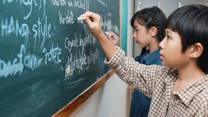Side view of asian boy writing engineering prompt and programing system while standing blackboard...