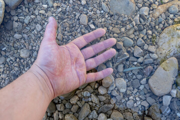 Adult hand underwater in rocky stream