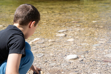 Boy picking up stones in the river 
