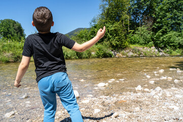 Boy throwing stones into the river 