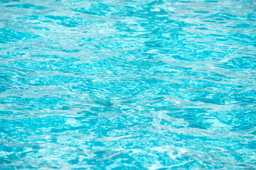 Water background. Blue water, ripples and highlights. Texture of water surface and tiled bottom.