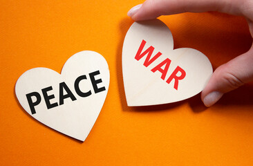War or Peace symbol. Concept word War or Peace on wooden hearts. Businessman hand. Beautiful orange...