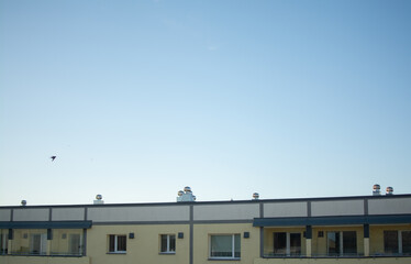 Rooftop ventilation pipes and chimneys on a modern residential building under a clear evening sky