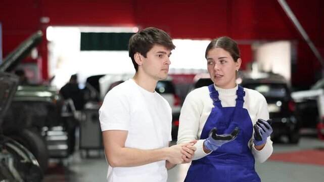 European guy consults with a car service worker about the repair and diagnostics of the car. Female mechanic gives recommendations for changing the oil, filter and checking the engine. High quality 4k