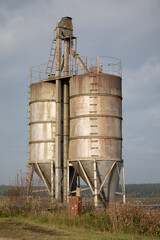 Rusty, abandoned industrial grain silos under a cloudy sky