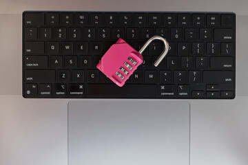 Close-up of pink combination lock on computer keyboard, representing internet security and online...