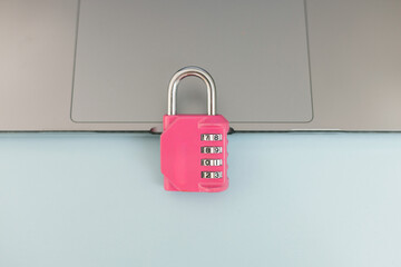 Pink combination padlock placed on a laptop, symbolizing cybersecurity, data protection, online...