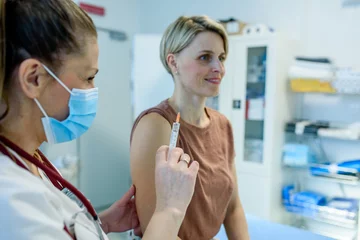 Fototapete Doctor administering vaccine to woman's arm during routine immunization © Halfpoint
