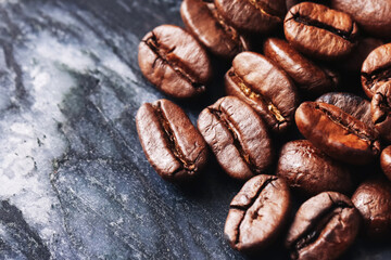 Roasted coffee beans macro shot. Dark aromatic seeds on black marble background. Fresh energy boost...
