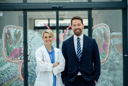 Male hospital manager standing next to female doctor, medical setting.