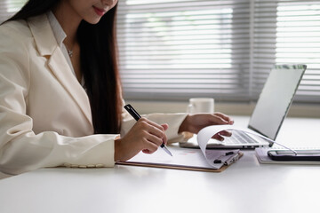 A woman is taking notes on a desk.