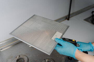 Close-up of unrecognizable cleaning service worker wearing gloves disinfecting kitchen extractor...
