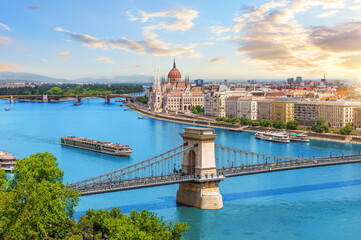Chain Bridge and Parliament building in Budapest, view of Danube River at sunset with riverboats