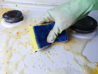 Housewife washes dirty gas stove with sponge and detergent with gloves, cleaning, cleaning soiled stove for cooking.